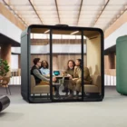 Framery Four with people talking inside inside a large open workspace